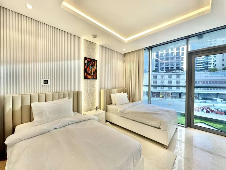 Twin bedroom with upholstered headboards and a floor-to-ceiling window