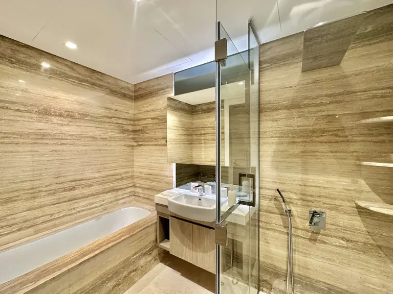 Bathroom with stone-look walls, a built-in bath and a glass shower