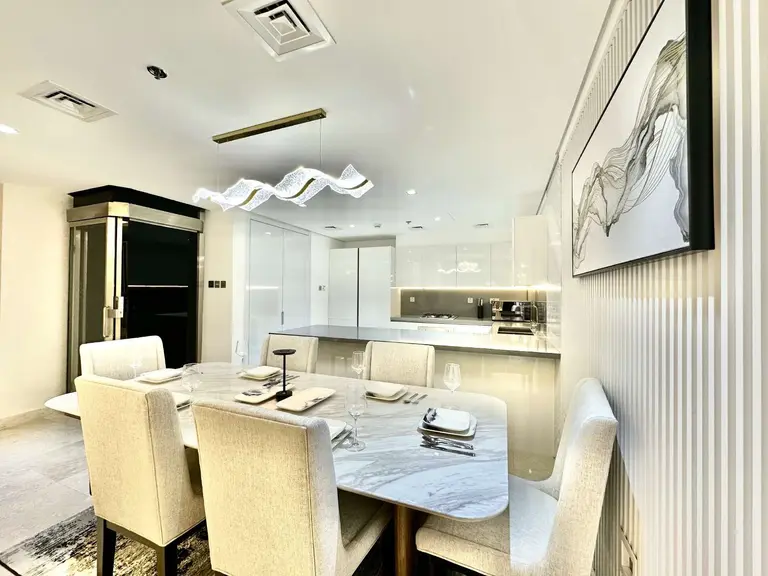 Six-seat dining table with a sculpted pendant light and the kitchen behind