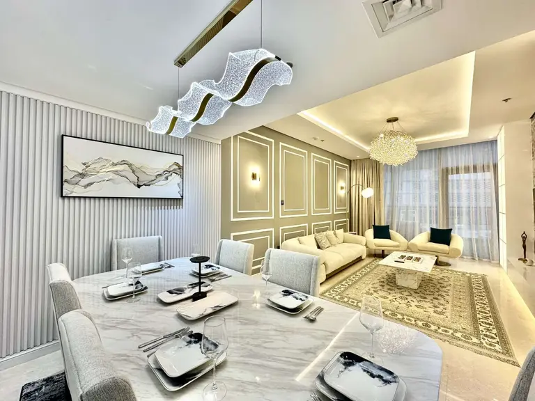 Open-plan living and dining room with a marble-look dining table, sculpted pendant light and cream sofas