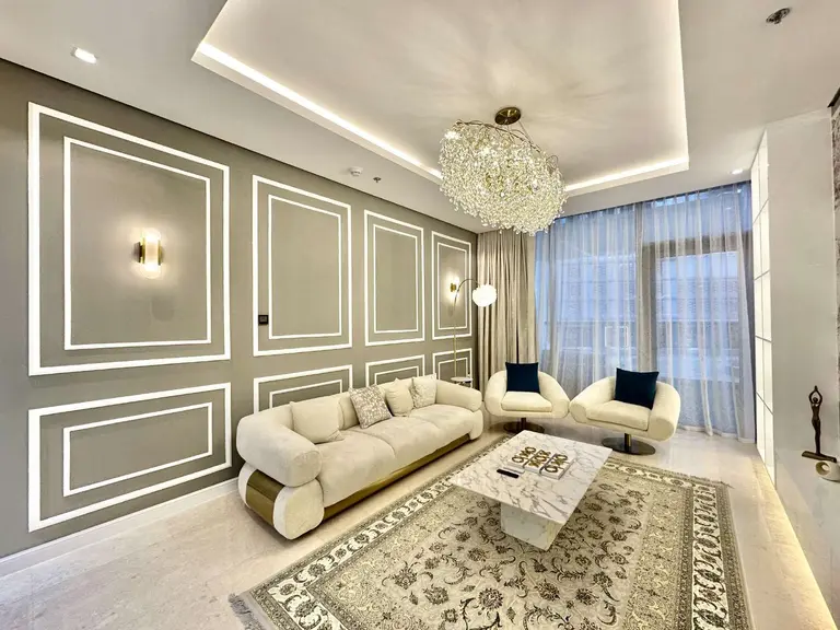 Living room with panelled walls, a curved cream sofa and a chandelier