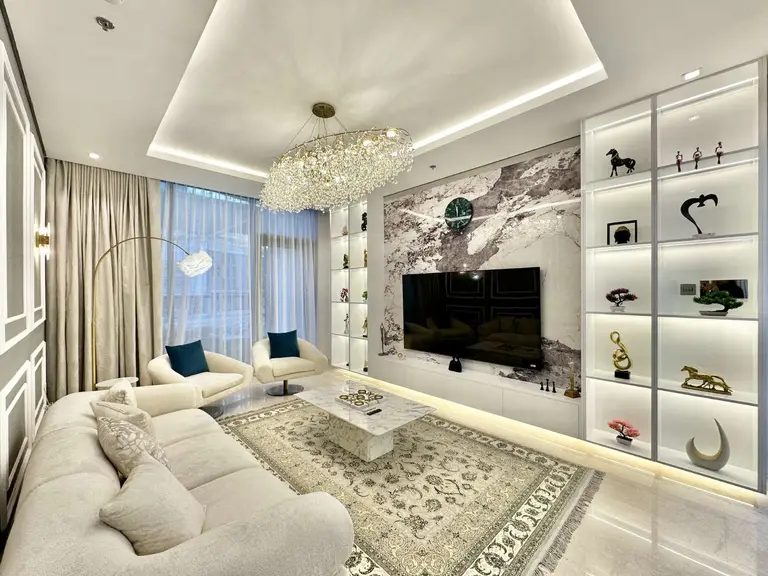 Living room with a marble-look feature wall, lit display shelves and a cream sofa