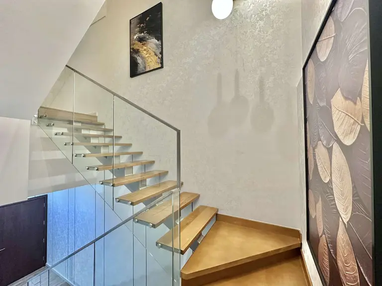 Floating stairs with wood-look treads and a glass balustrade
